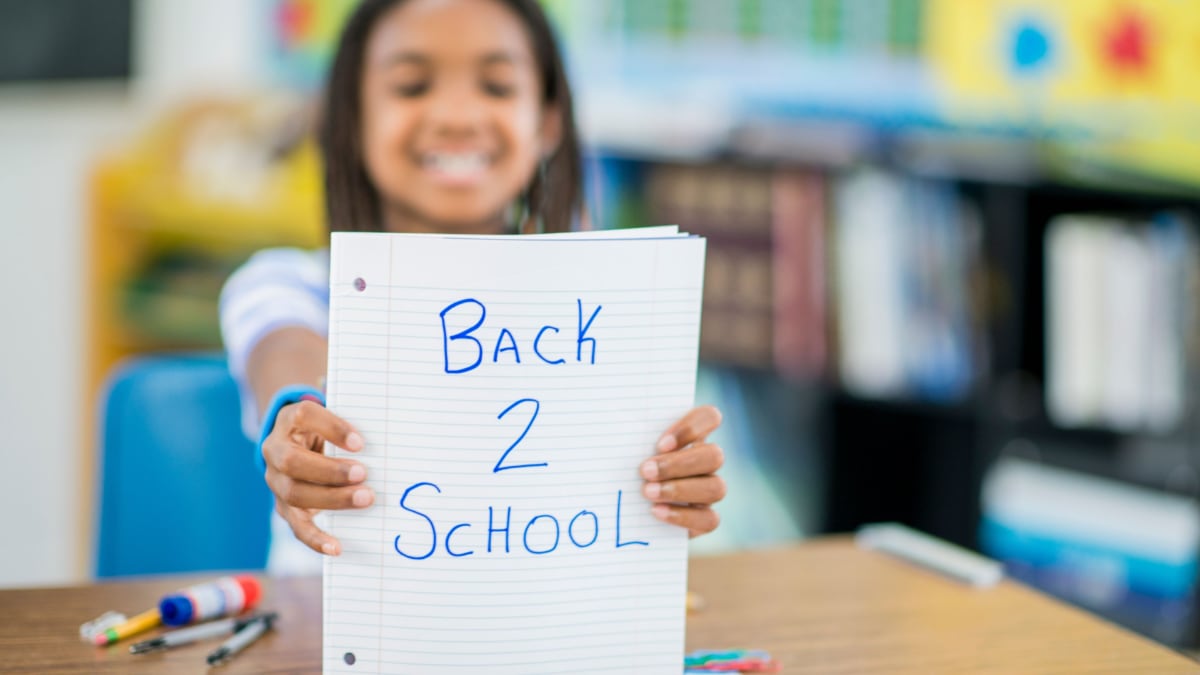 girl holding paper with back 2 school written on it