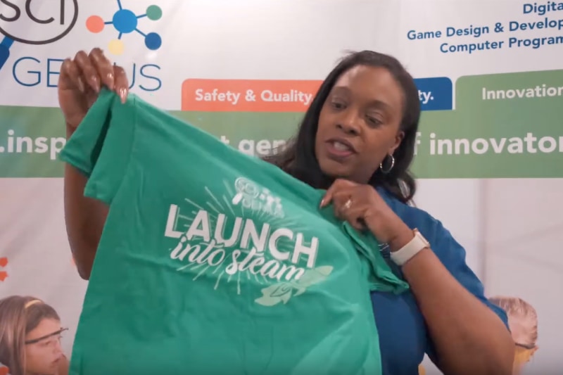SciGenie director holding up green camper t-shirt