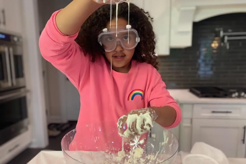 young girl with safety goggles playing with a goo-like substance in a kitchen