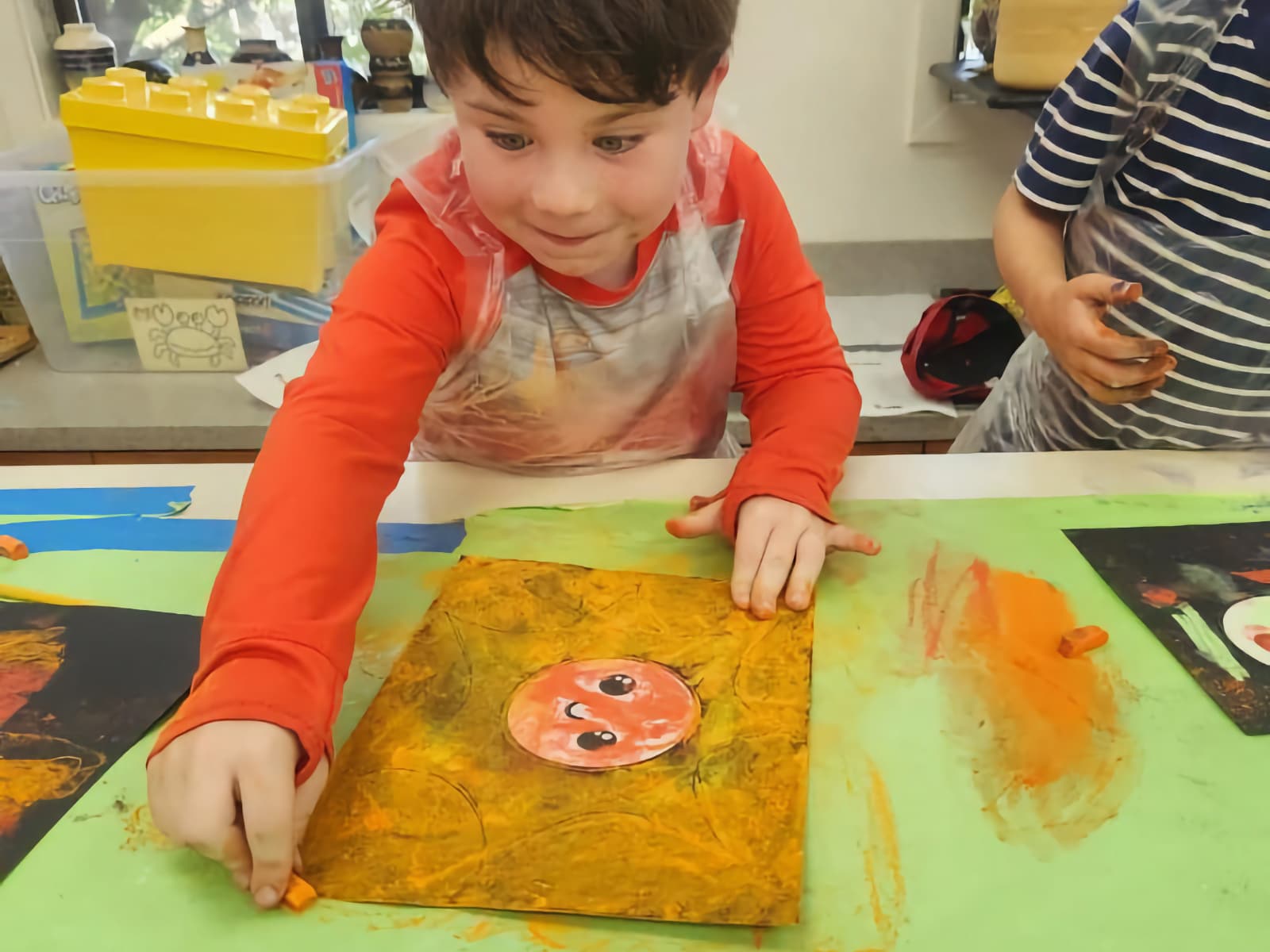 little boy coloring a sun with pastels