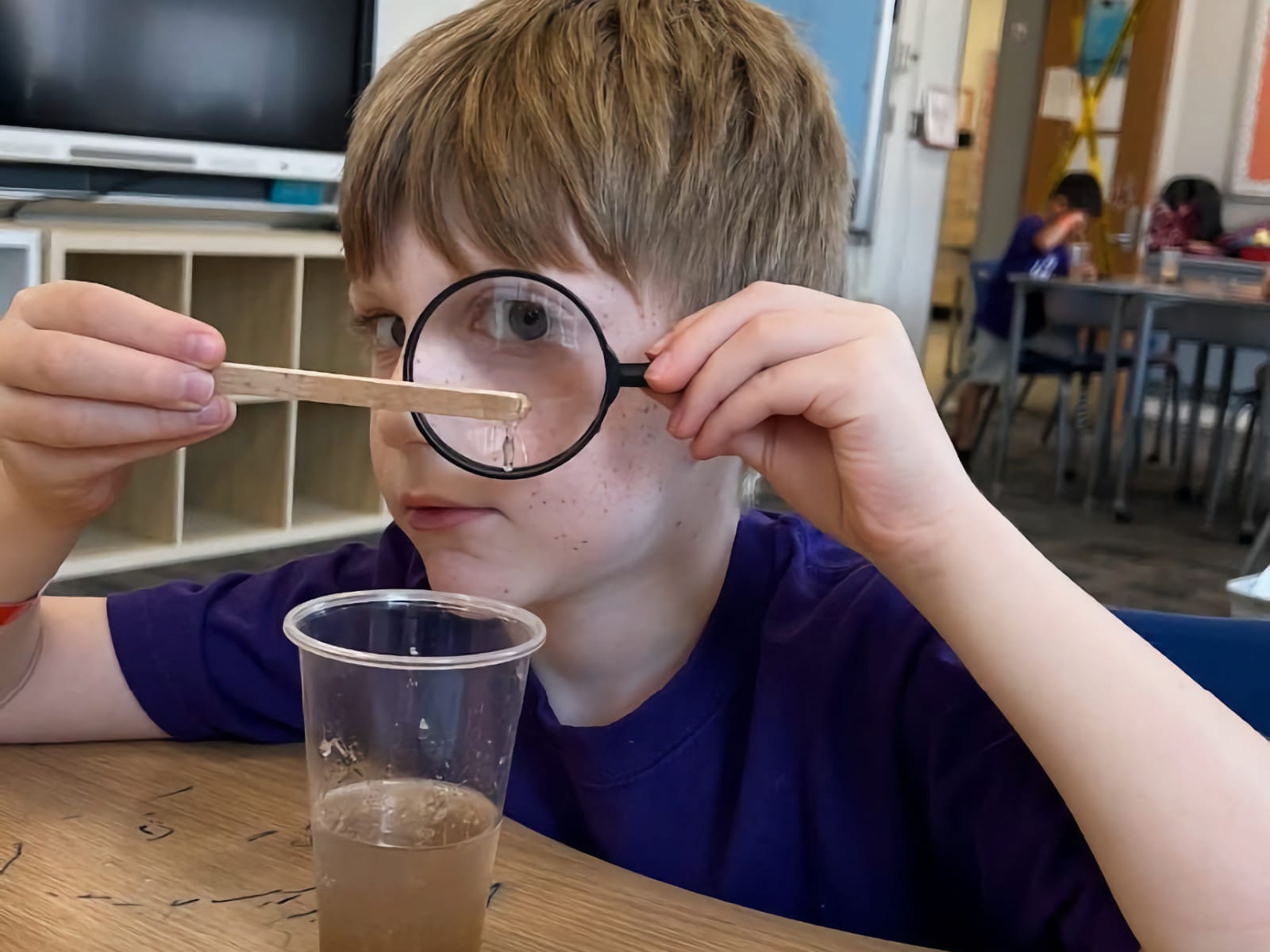 young boy looking at something close up with a magnifying glass