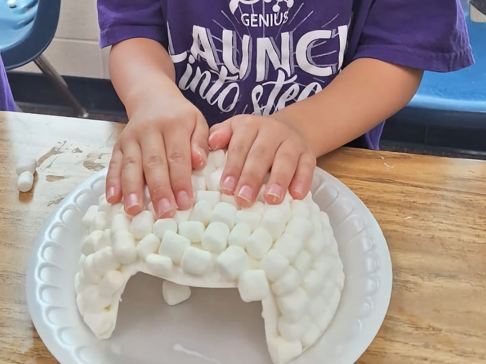 little hands pressing down on marshmallow igloo