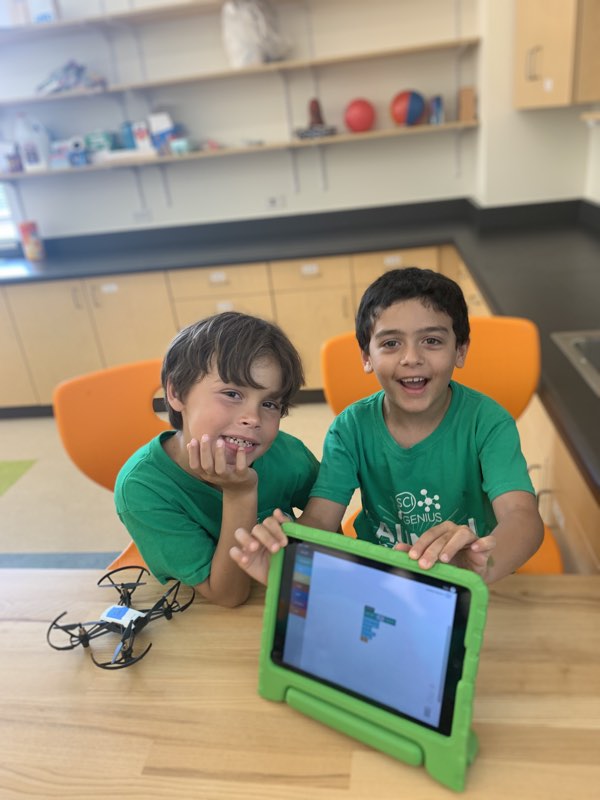 two young boys programming a drone on a tablet