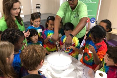 A SciGenie instructor performing an experiment with a group of kids.