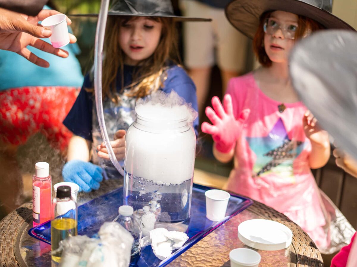 girls with wizard hats in wonder at a potion experiment