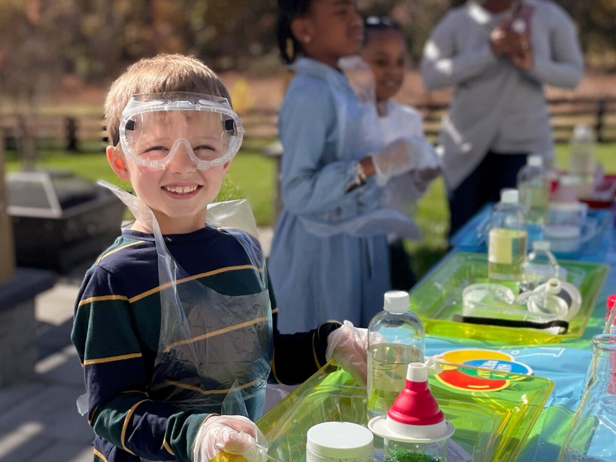 boy wearing safety goggles in front of experiments set up on a table