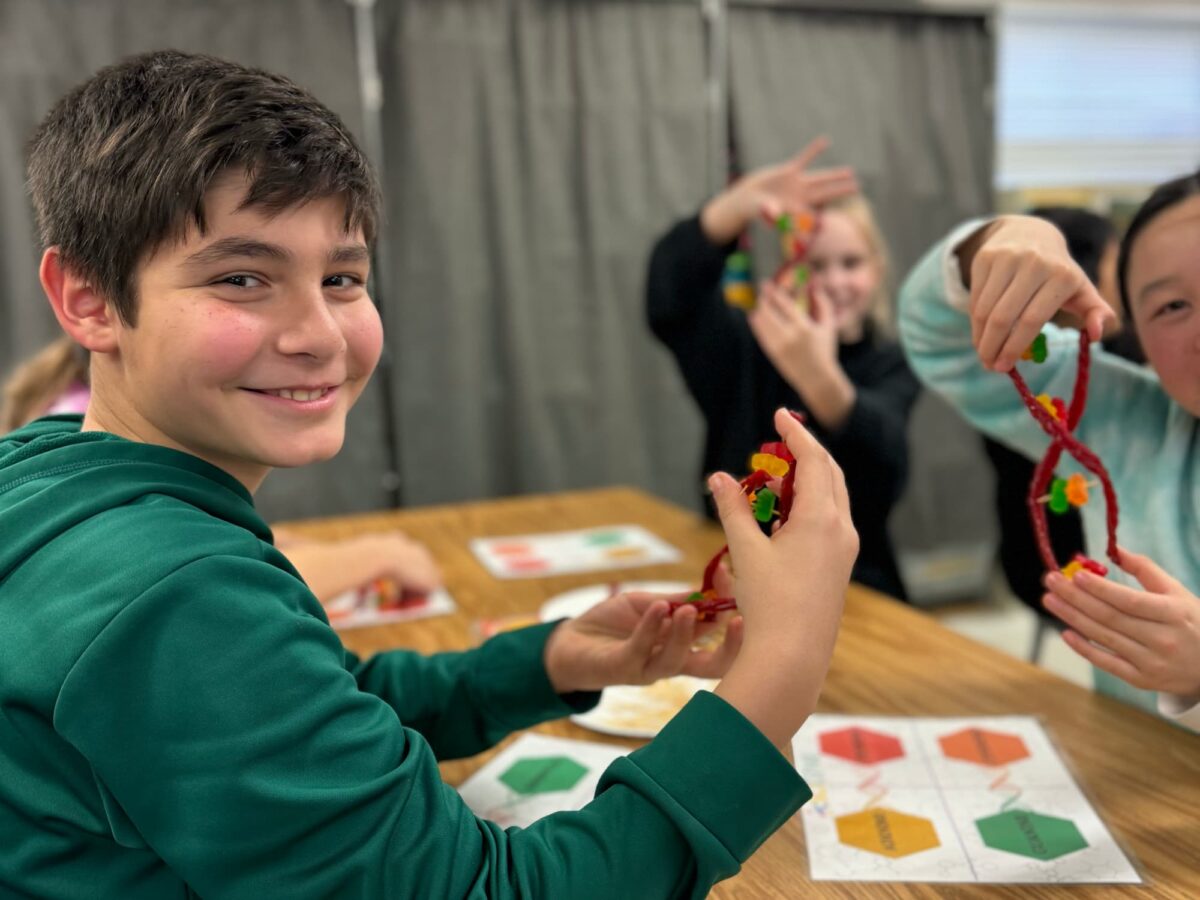 boy holding DNA strand model and smiling at camera