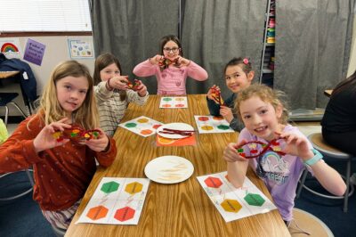 A group of young kids holding up a science project made of candy.