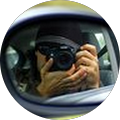 person pointing a professional camera at a car side mirror