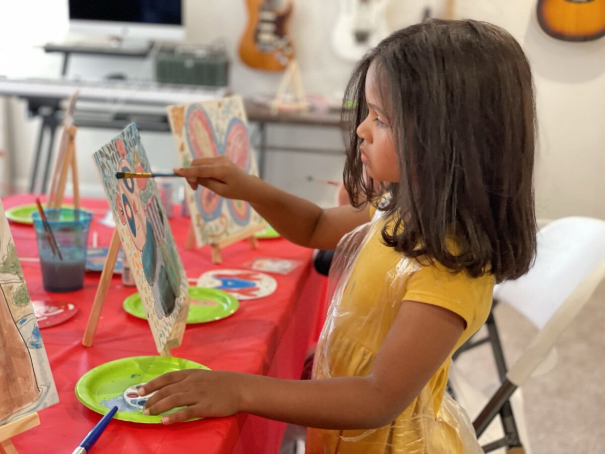 girl painting a bear on a cavas sitting on an easel