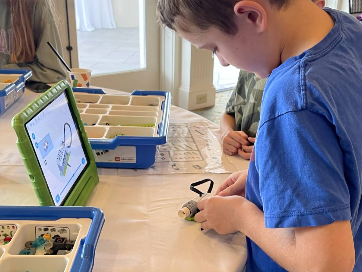 boy building a robot with LEGO while viewing a 3D model on a tablet
