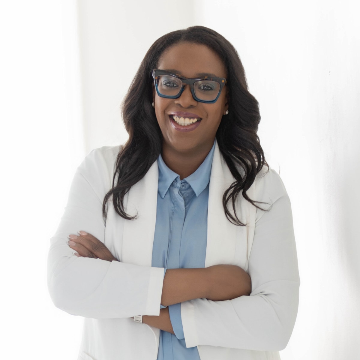 SciGenie Founder Alicia McEldon; a smiling woman with long flowing hair and blue rimmed glasses