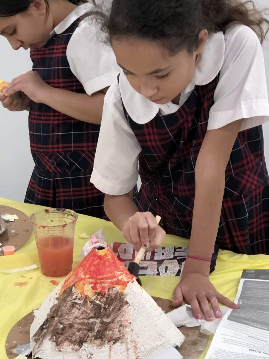 girl in school uniform painting a volcano