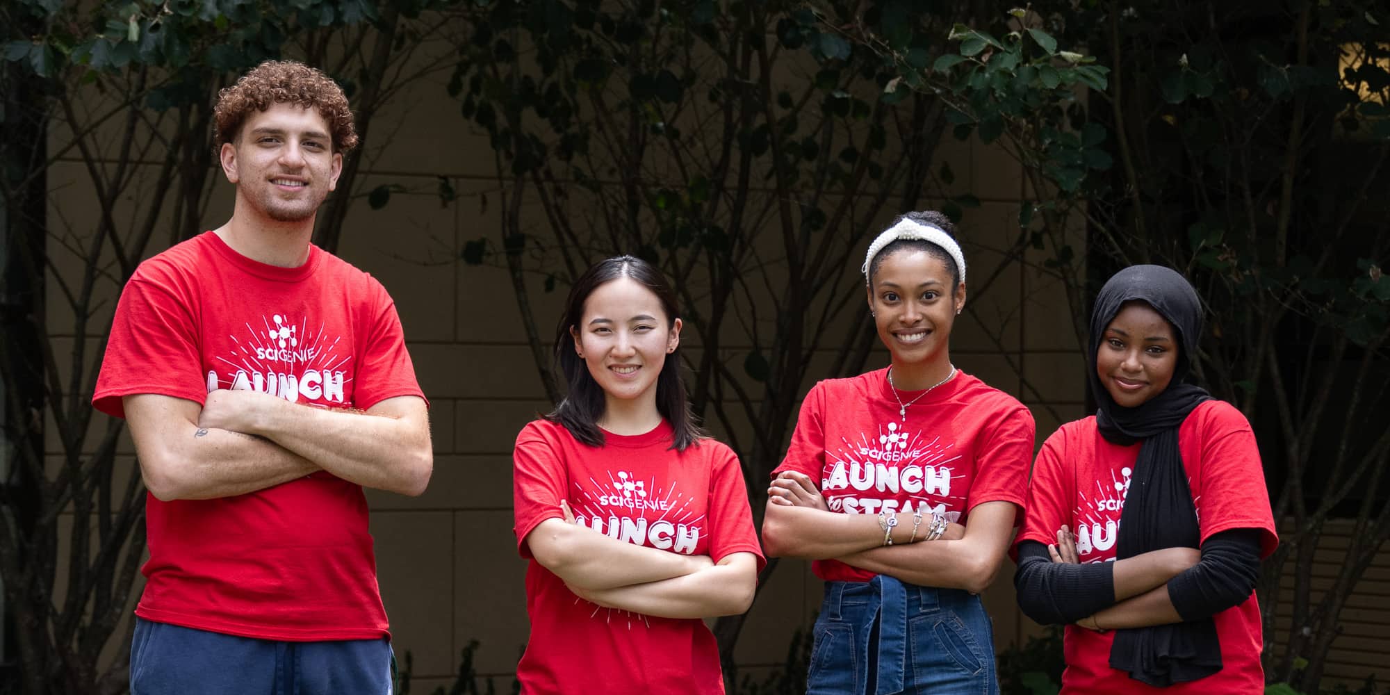 four smiling camp counselors with arms crossed