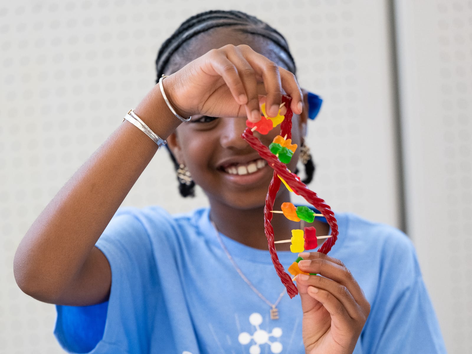 smiling girl looking at the double helix she made out of candy