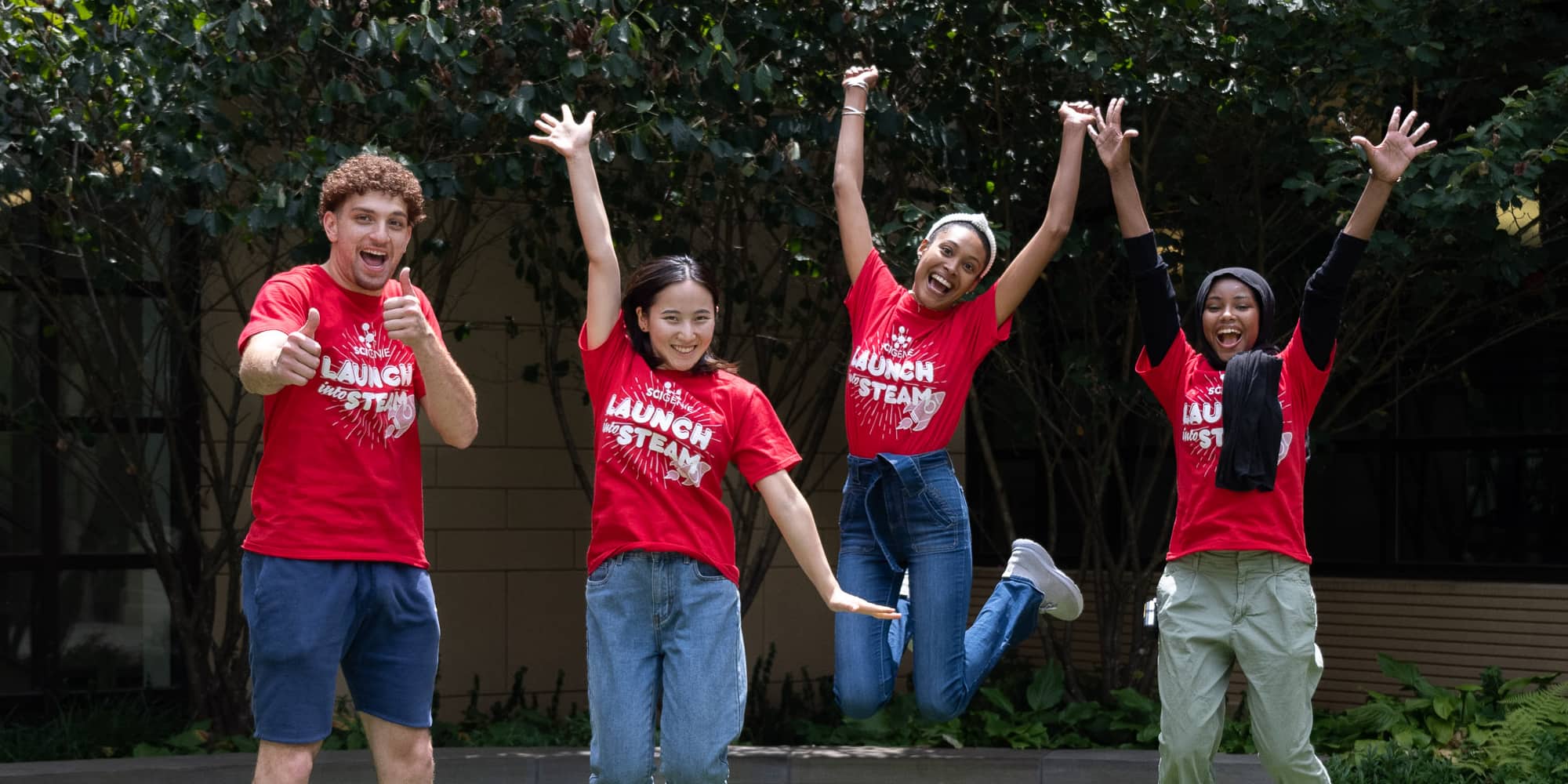 four smiling camp counselors jumping up into the air