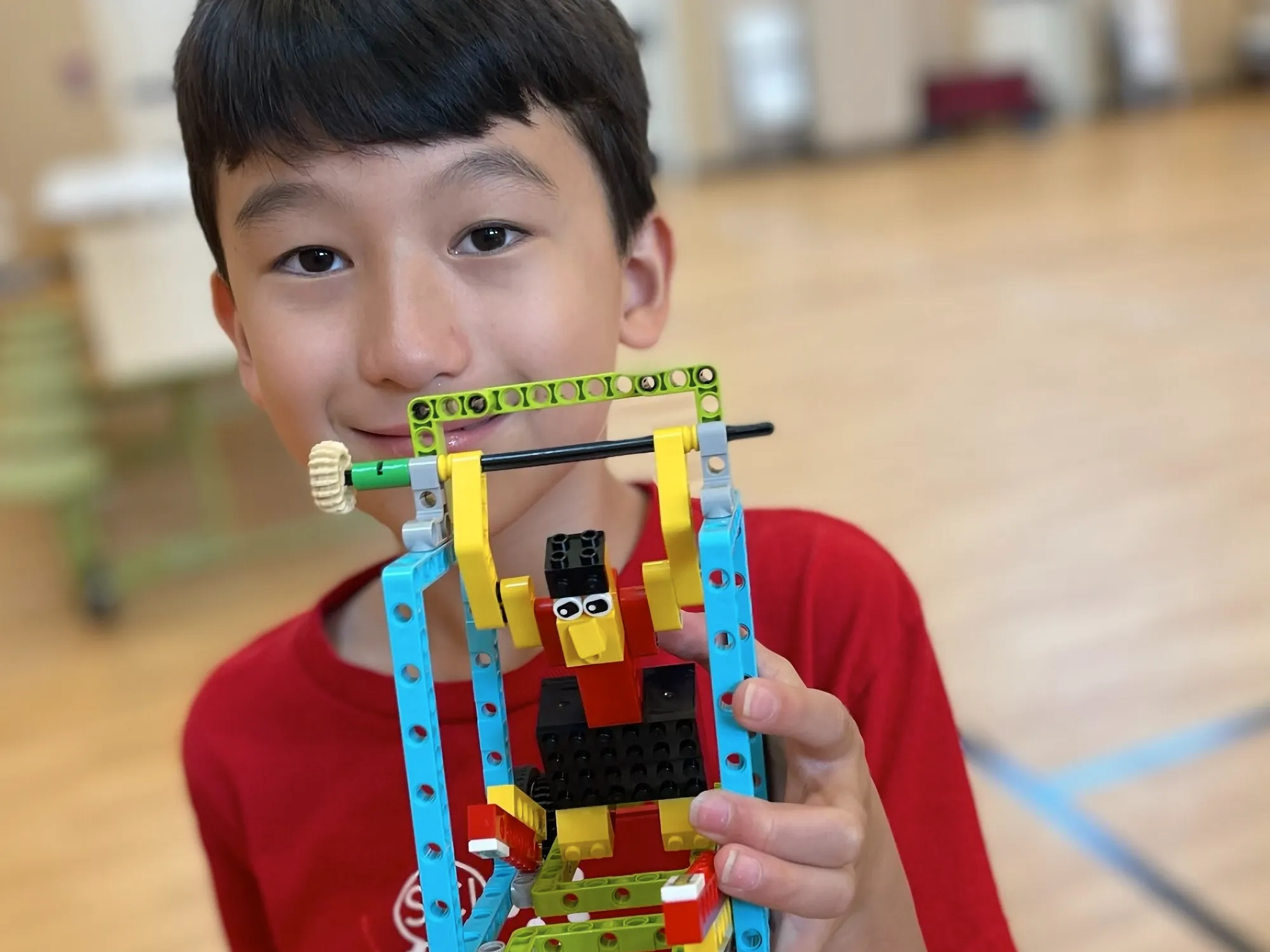 A young camper holding a LEGO robotics model.