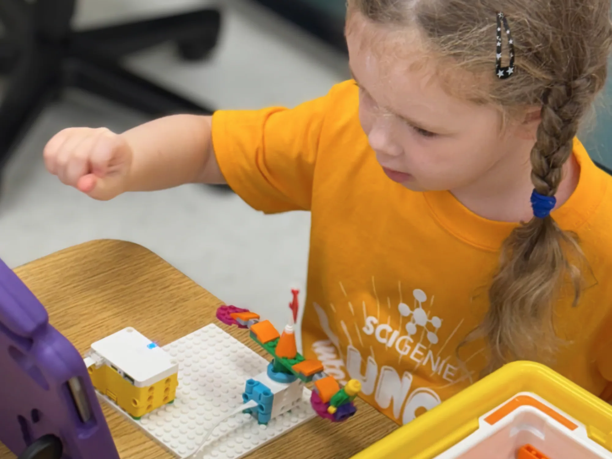 Young camper working on a LEGO model a looking at a tablet.