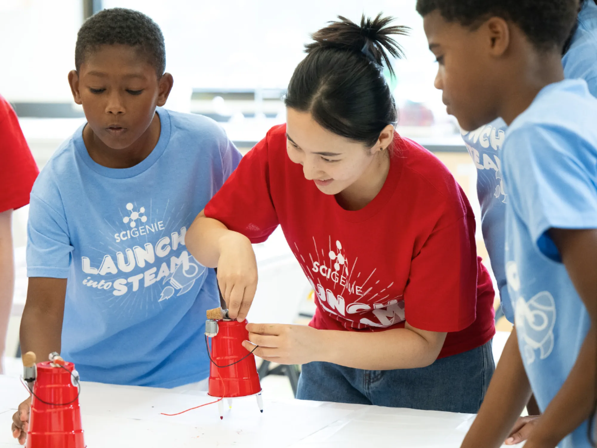 A camp counselor showing campers an experiment with a red solo cup.
