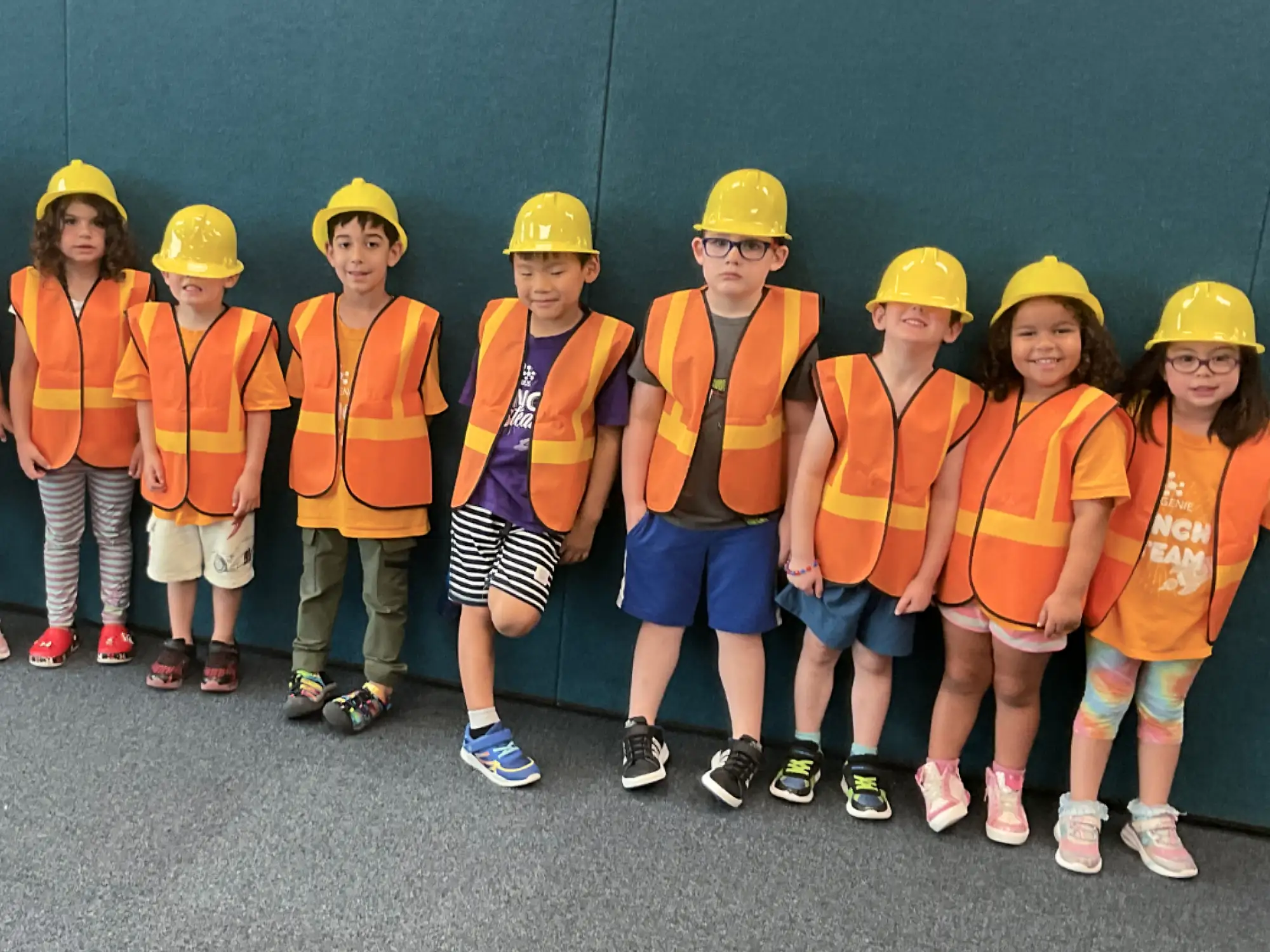 A line of young campers in construction hats and vests.